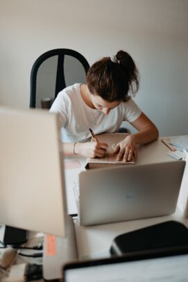 Photo by Finde Zukunft woman in white shirt writing on white paper